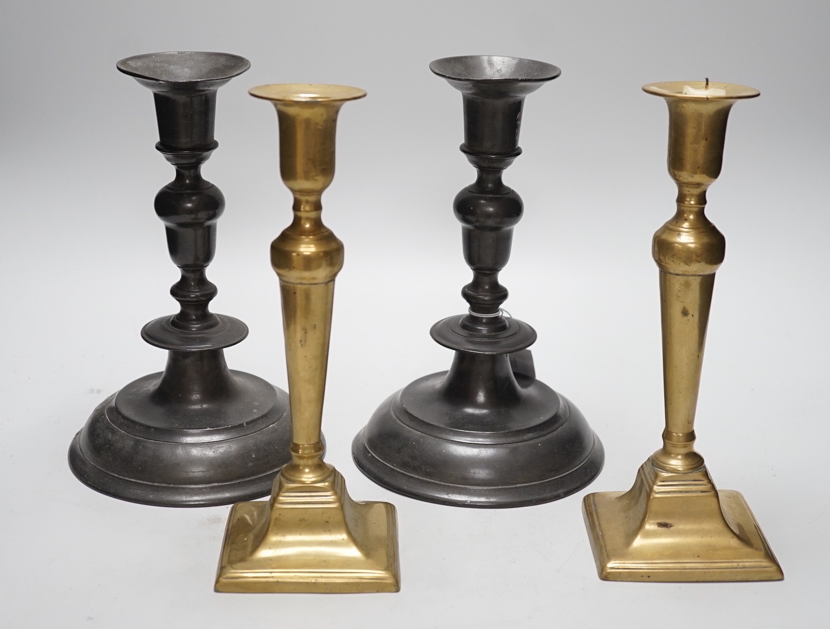 A pair of 18th century continental, possibly German, pewter candlesticks- 24cms high and a pair of late Georgian brass candlesticks